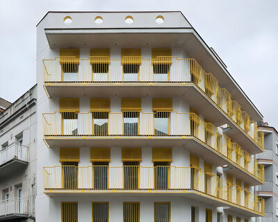 yellow steel, concrete, and circular openings revive corner building in spain as apart-hotel