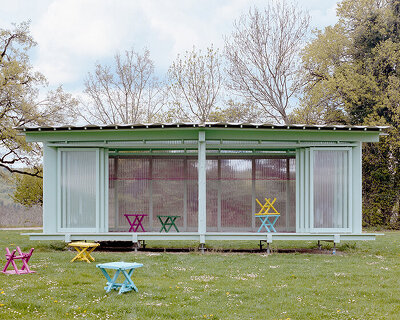 sliding timber frames and reused materials shape reversible pavilion within swiss meadow