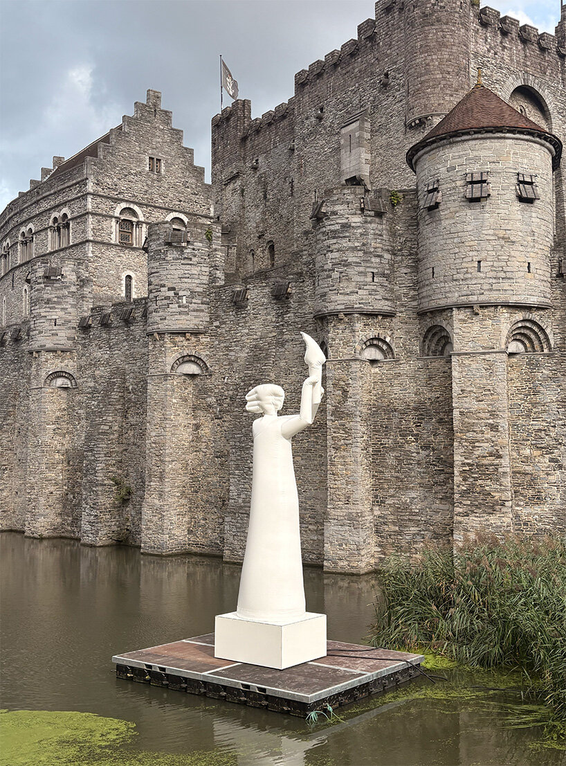 the inflatable figure stands in front of the crenellated walls of Gravensteen