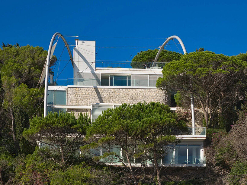 Villa exterior with curved steel arches, stone walls, and glazed facades